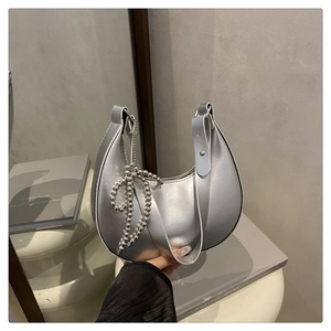 Détail du sac croissant argenté avec fini métallique liquide et nœud en perles