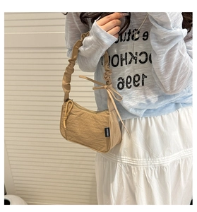 Détail d'un sac à bandoulière en nylon kaki avec un nœud latéral et une anse froncée