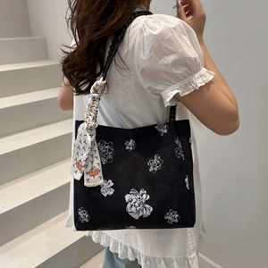 Large black tote bag with white floral print and decorative silk scarf on shoulder strap