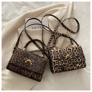 Détail de deux sacs léopard avec boucles nœud doré et bandoulières réglables amovibles