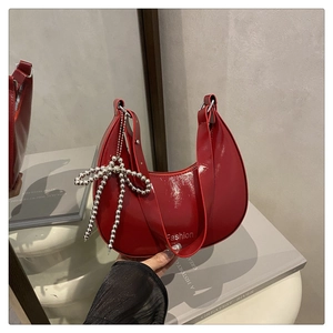 Détail du sac hobo en cuir verni rouge avec breloque nœud argenté et texte fashion