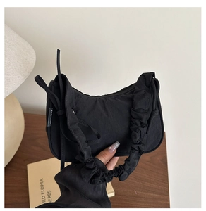 Détail du sac croissant noir avec poignée froncée de style scrunchie et tissu minimaliste
