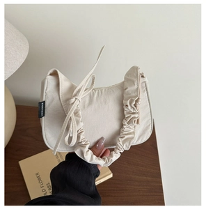 Détail du sac hobo en textile beige avec anse froncée et étiquette de marque FANYISSA