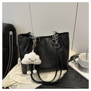 Detail of a black woven leather tote bag with silver chain straps and cloud charm