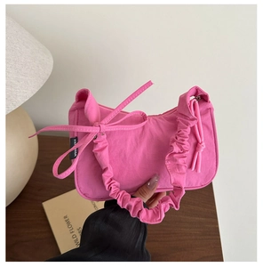 Gros plan du sac à main croissant rose avec poignée froncée et détail de nœud