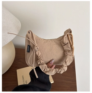 Détail du sac à main beige plissé avec anse froncée et nœud décoratif élégant