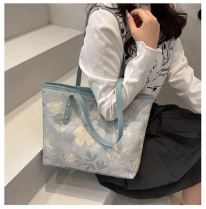 Détail d'un grand sac cabas bleu à fleurs avec des motifs peints et des rivets dorés
