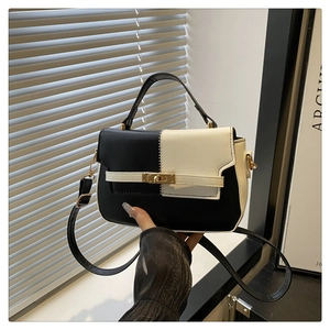 Detailed close-up of the black and white contrast PU leather bag with golden metal buckle