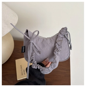 Détail du sac à bandoulière gris-violet avec bandoulière plissée et nœud décoratif