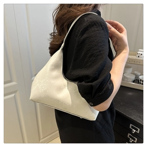 Detail showing the white textured crescent shoulder bag with embossed fashion letters