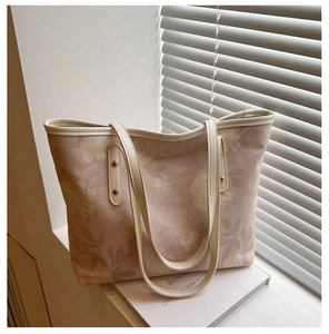Détail d'un sac cabas rose à imprimé floral avec motifs de feuilles et rivets métalliques