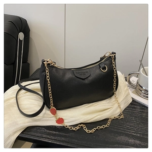 Detail der schwarzen Tasche mit Goldkette und roten Erdbeer-Anhängern