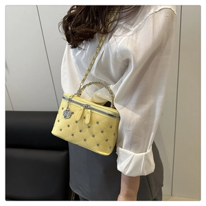 Close-up of quilted yellow leather crossbody bag with chain strap and flower charm