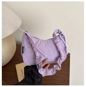 Détail du sac à bandoulière lavande avec sangle froncée et étiquette latérale stylée