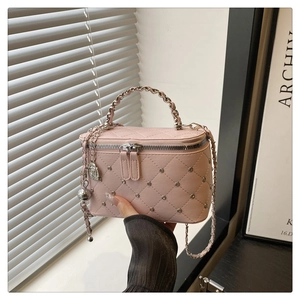 Close-up of pink quilted faux leather bag with silver rivets and metallic chain handle
