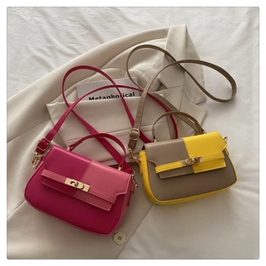 Detail view of contrast color crossbody bags with metal twist locks on a lifestyle backdrop