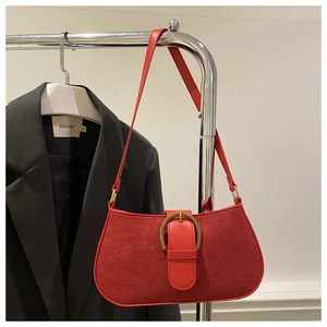 Detail einer roten Vintage-Wildledertasche mit goldener Hufeisenschnalle und Lederriemen