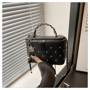 Close-up of black quilted box bag with silver studs, chain strap and camellia charm