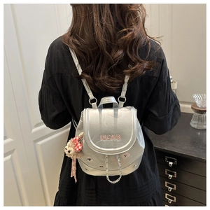 Silver mini backpack with IBCMB embroidery and red plaid bear charm shown on model