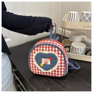 Detail of red checkered canvas bag with denim heart patch and white lace trim