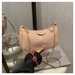Detailansicht der rosa Lederhandtasche mit Goldkette und rotem Erdbeer-Anhänger-Dekor