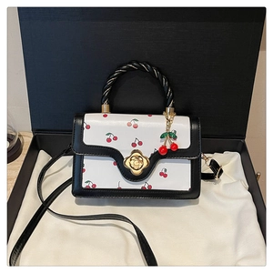 Vue détaillée du petit sac carré à motif cerise avec fermoir fleur et boîte de luxe
