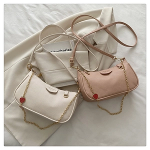Details von cremefarbenen und rosa Ledertaschen mit litchi-struktur und erdbeere-goldketten