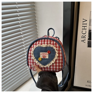 Detail of red checkered mini backpack featuring denim heart patch and lace trim details