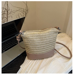 Close-up of woven straw bucket bag with pink leather trim and silver zipper closure