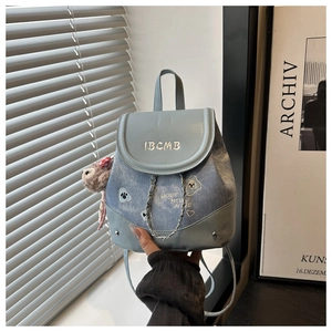 Gros plan sur un mini sac à dos bleu clair brodé avec chaîne et pendentif agneau