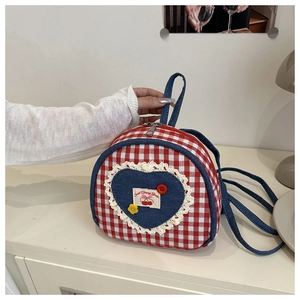 Detail of red checkered backpack featuring denim heart patch with lace and cherry embroidery