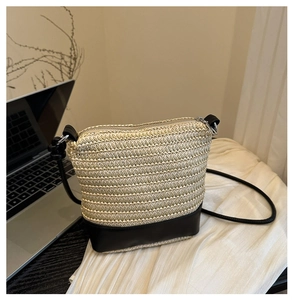 Detail of woven straw texture with black leather trim on a stylish crossbody bag