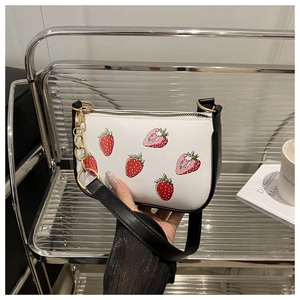 Détail du sac à main fraise avec bandoulière noire et chaîne décorative en métal doré