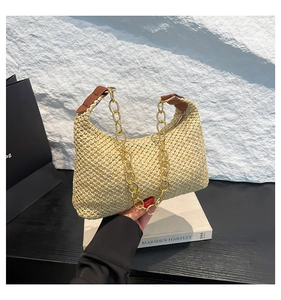 Dettaglio borsa hobo intrecciata a mano con catena dorata su supporto per libri
