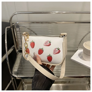 Détail du sac blanc avec imprimés fraises rouges et chaîne métallique dorée chic