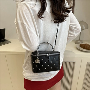 Quilted black crossbody bag with silver rivets and rose charm worn by a model