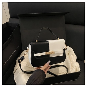 Detail of contrast stitch handbag featuring metallic turn-lock and premium leather texture