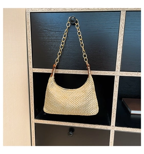 Dettaglio della borsa hobo in paglia intrecciata con catena dorata e inserti in pelle