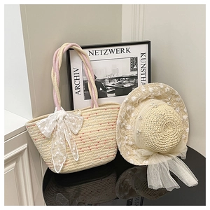 Detail of straw bucket bag and hat set with lace bows on a reflective surface