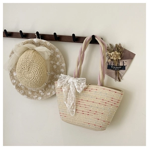 Handmade woven straw bag with pink braided handle and matching sun hat set on wall hooks