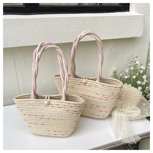 Detail of straw woven bucket bags with colorful dots, pearl clasp and braided handle
