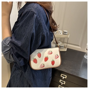 Détail du sac sous l'aisselle à imprimé fraise avec bordure en cuir marron et zip
