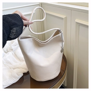 Close-up of cream white bucket bag featuring lychee texture leather and rope strap