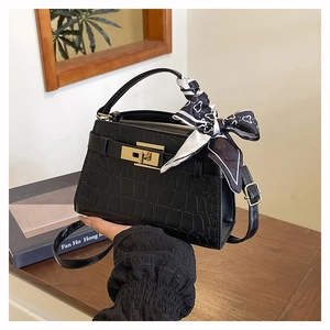 Detail of black crocodile pattern handbag with gold twist lock and printed silk scarf