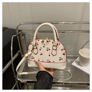 Detailed view of cherry print shell bag with dual gold zippers and smooth PU leather edges
