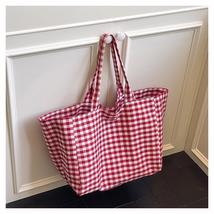 Detail of red and white gingham canvas tote bag hanging on a minimalist white cabinet door