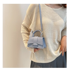 Detail view of mini blue denim hourglass bag with top handle and metal ring buckle
