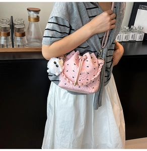 Détails du sac seau rose avec motifs nœuds noirs et breloque petit monstre en peluche