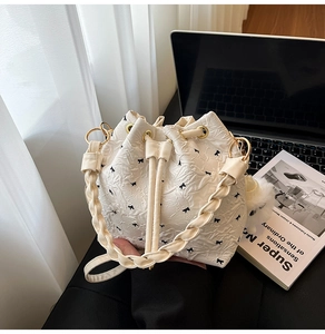 Détail du sac seau plissé blanc avec broderies de nœuds noirs et anses tressées