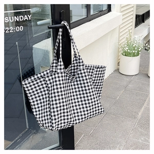 Detail view of checkered canvas tote bag hanging on a door handle in a sunny setting